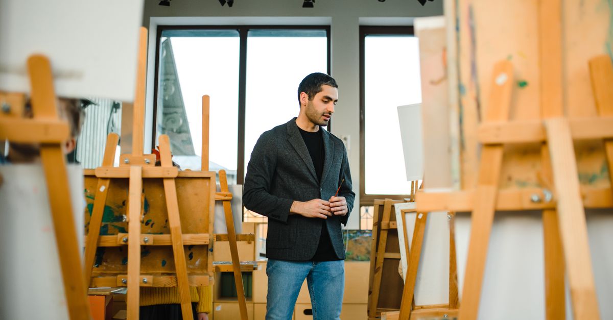 Young artist surrounded by easels in a contemporary art studio setting.